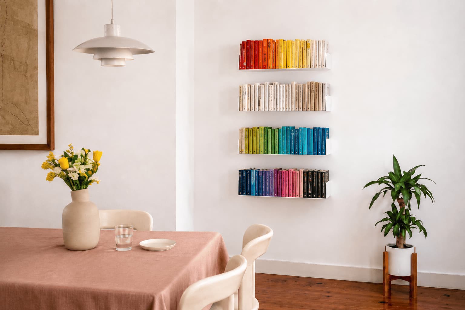 Bibliothèque avec livres classés par couleur créant un mur bibliothèque moderne dans une salle à manger lumineuse