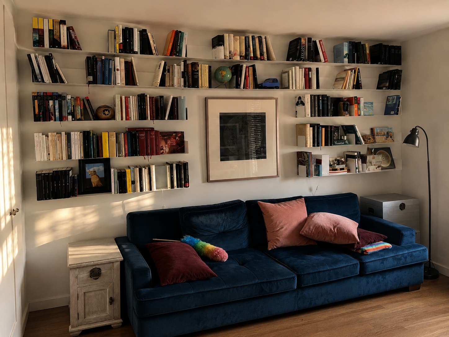 Bibliothèque murale composée de longues étagères remplies de livres au-dessus d’un canapé