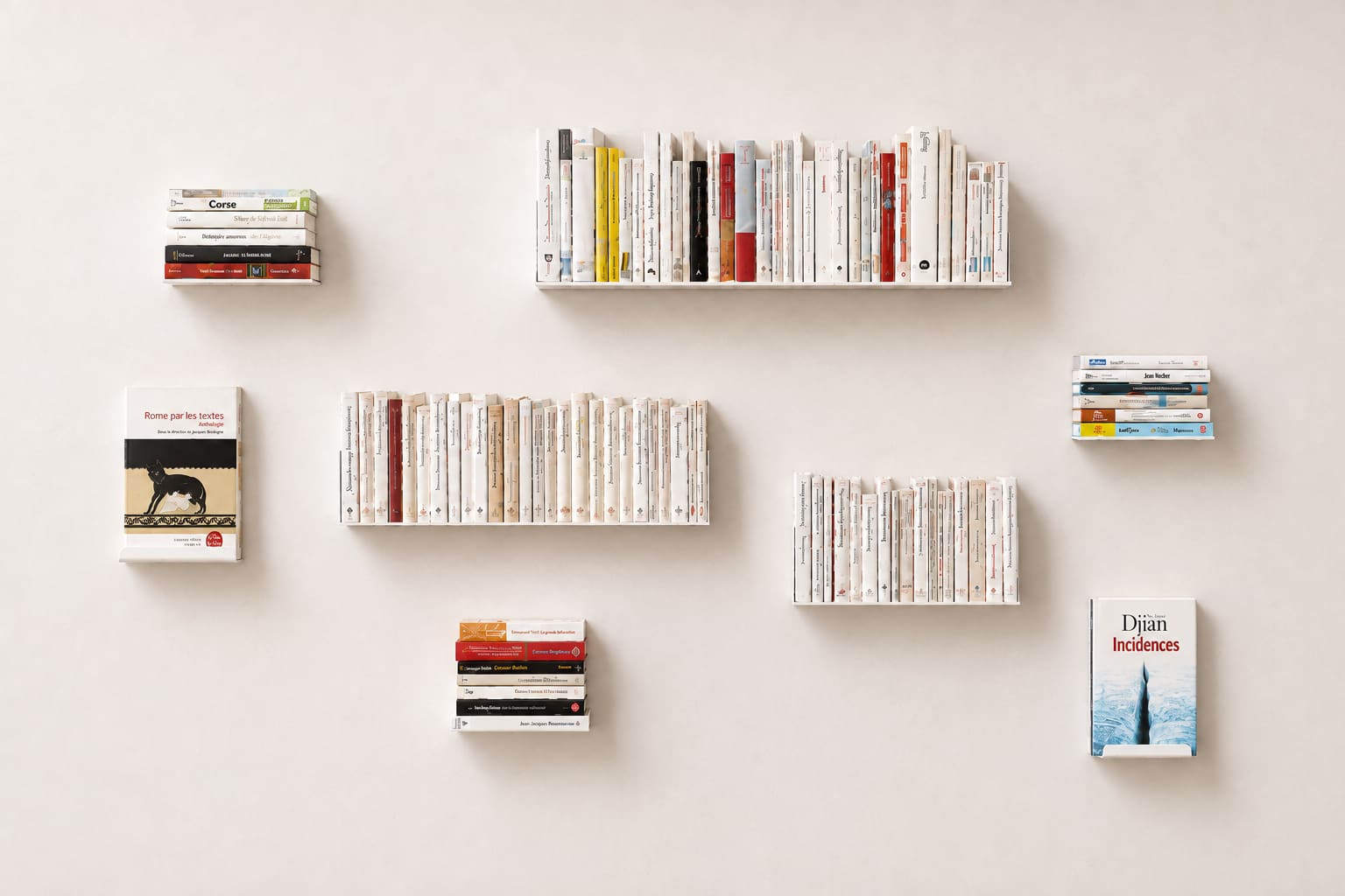 Composition de petites étagères murales blanches réparties sur un grand mur, avec des rangées de livres debout, des piles horizontales et quelques couvertures présentées de face.