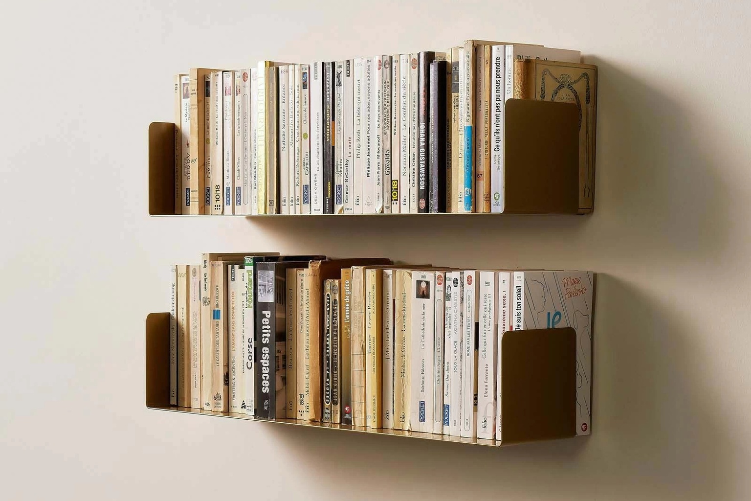 Étagères avec équerre invisible en finition or antique, fixées au mur et remplies de livres, avec des rebords latéraux discrets qui maintiennent les ouvrages dans un style mural élégant et minimaliste.