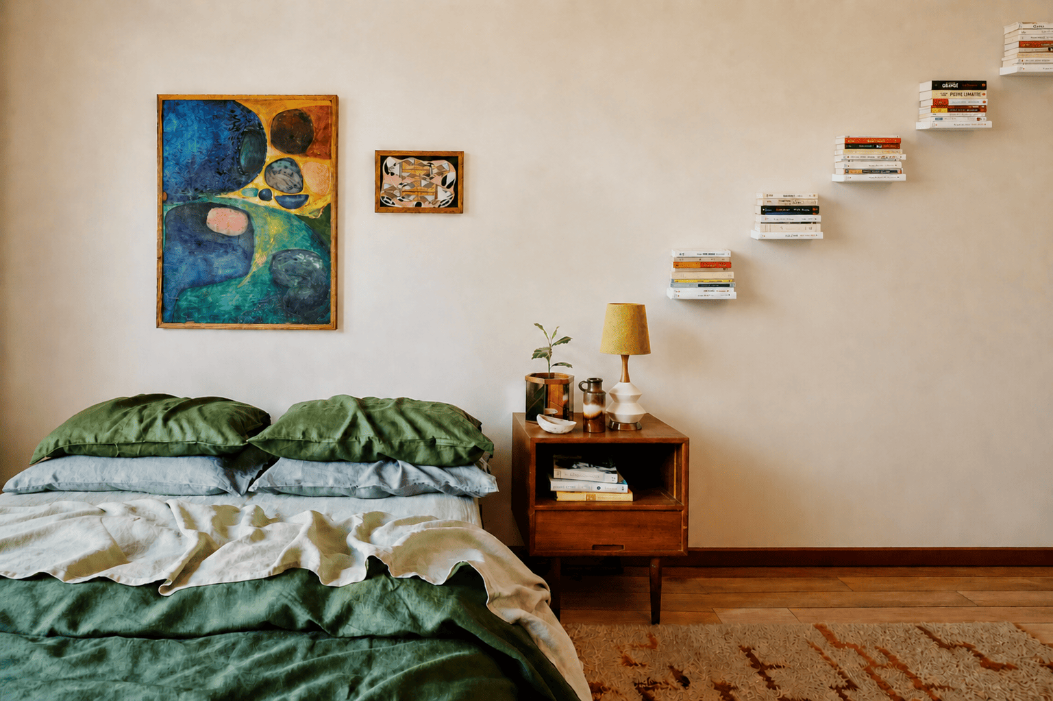 Étagère verticale murale blanche avec livres en lévitation disposée en escalier au-dessus d’une table de chevet dans une chambre design et minimaliste