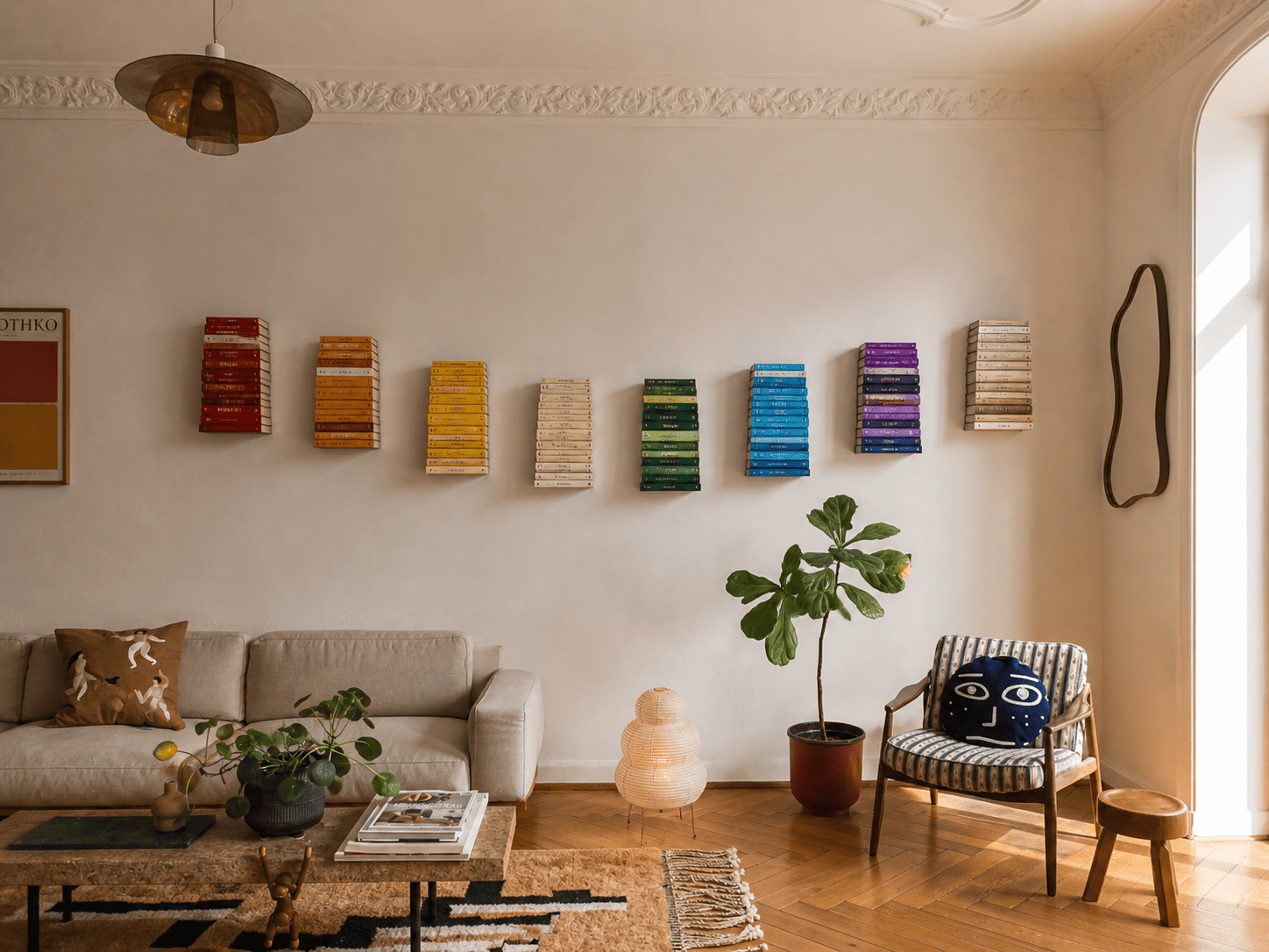 Étagères verticales colorées alignées au mur avec livres triés par couleur, créant une décoration graphique et contemporaine