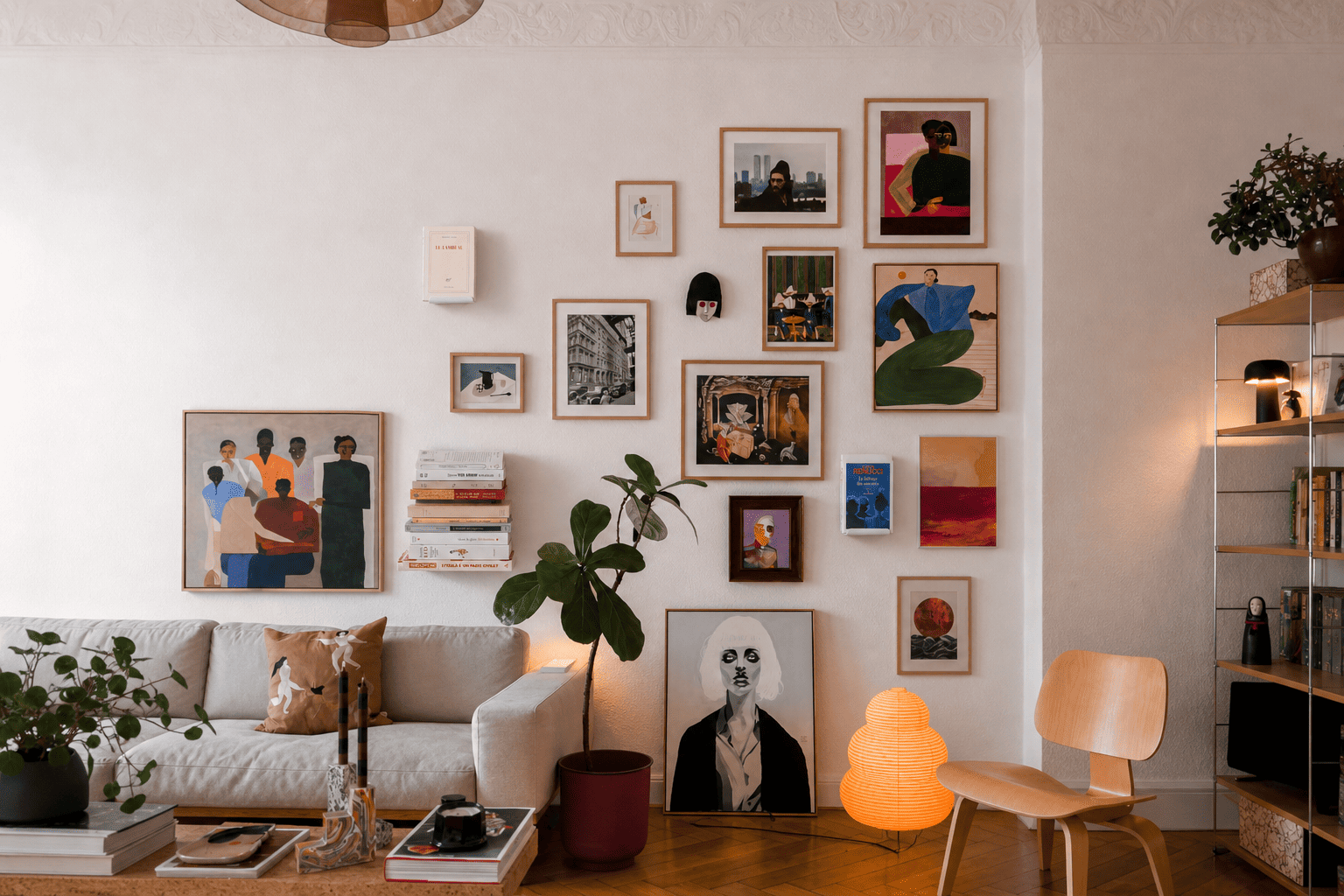 Étagère verticale intégrée dans une composition murale mêlant cadres, œuvres et objets, apportant du relief à un salon décoré avec soin
