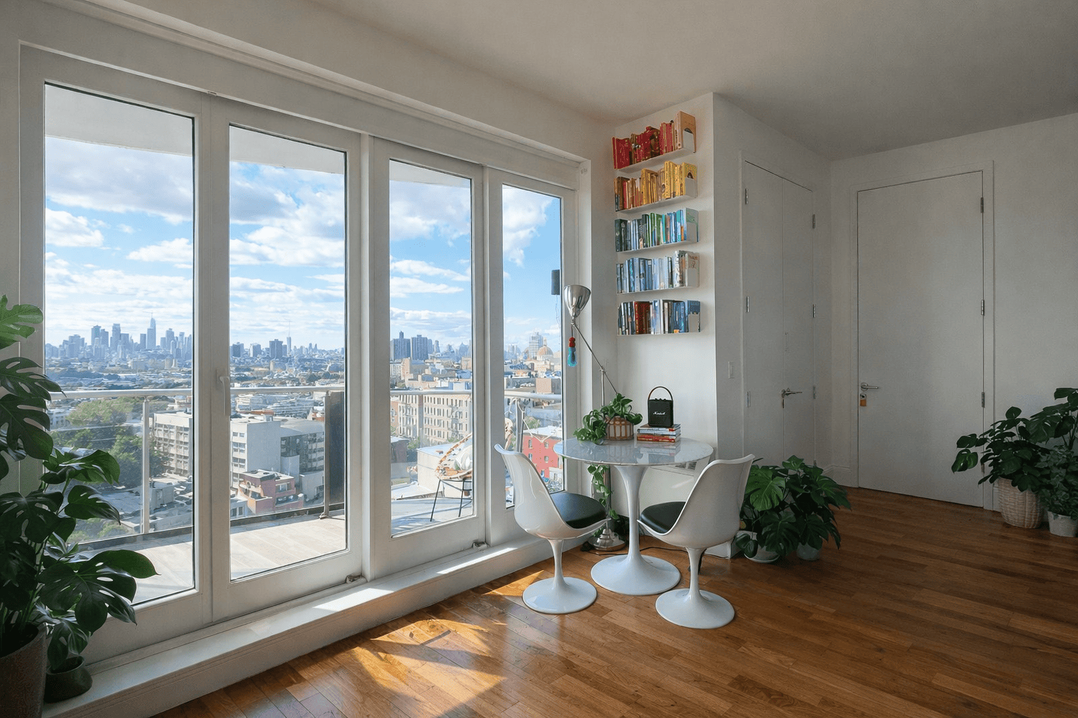 Étagères murales design avec livres colorés dans un appartement lumineux, élément de décoration moderne et minimaliste près d’une baie vitrée avec vue sur la ville.