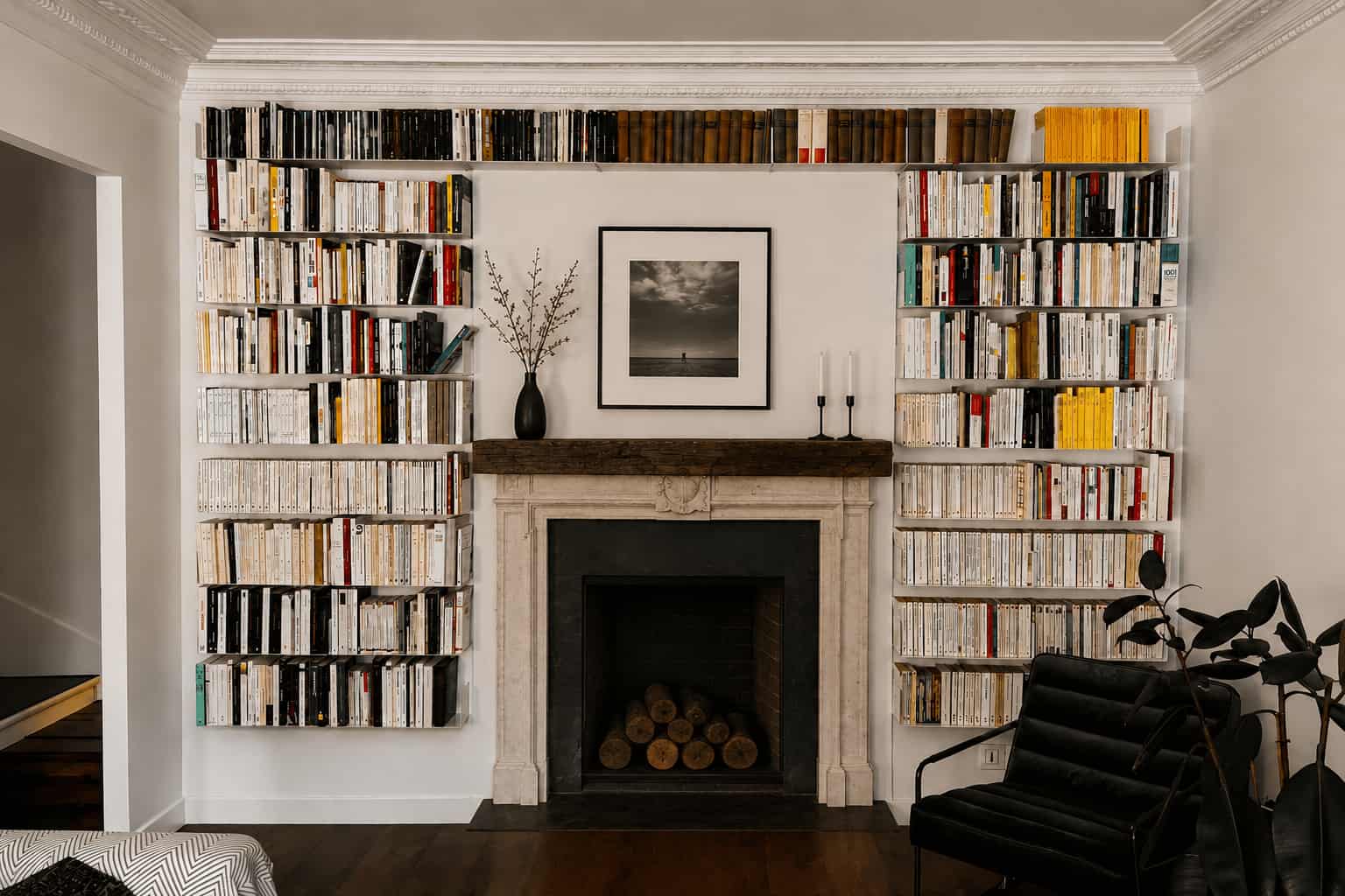 Idée de bibliothèque murale dans un salon avec étagères de livres aménagées autour d’une cheminée