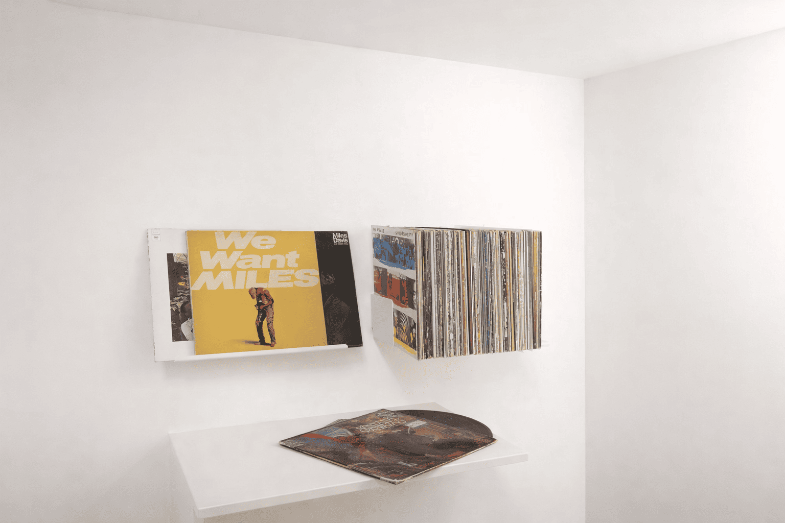 Porte vinyle mural blanc avec présentoir vinyle minimaliste affichant des pochettes dans un intérieur moderne