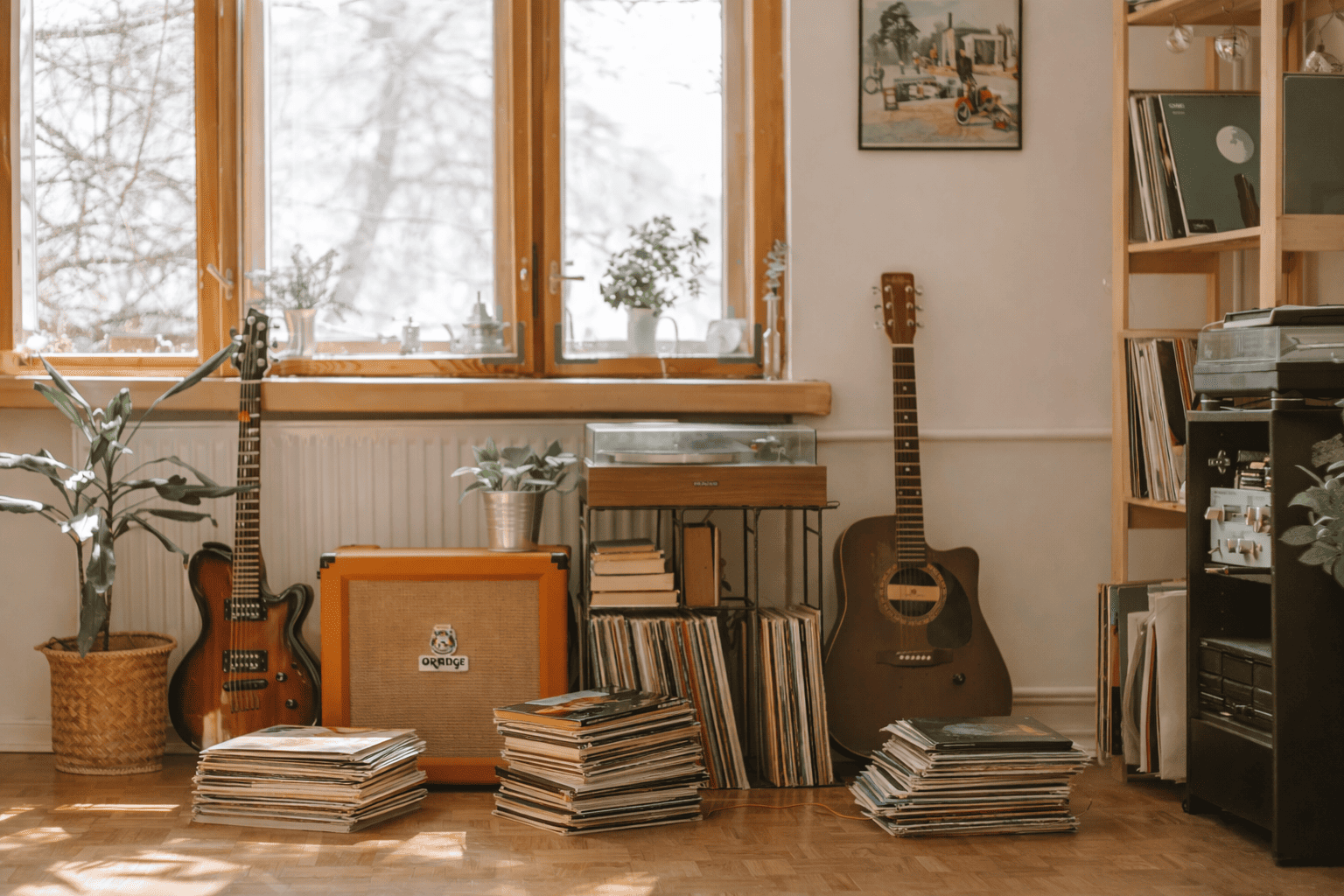 Espace d’écoute lumineux avec stockage de vinyle, meuble à platine, étagère de disques, guitares et pochettes vinyles empilées au sol
